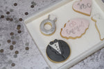 Decorated cookies to celebrate an engagement, dress cookie, suit cookie, initials heart cookie, ring cookie and plaque with engaged stamped on it.